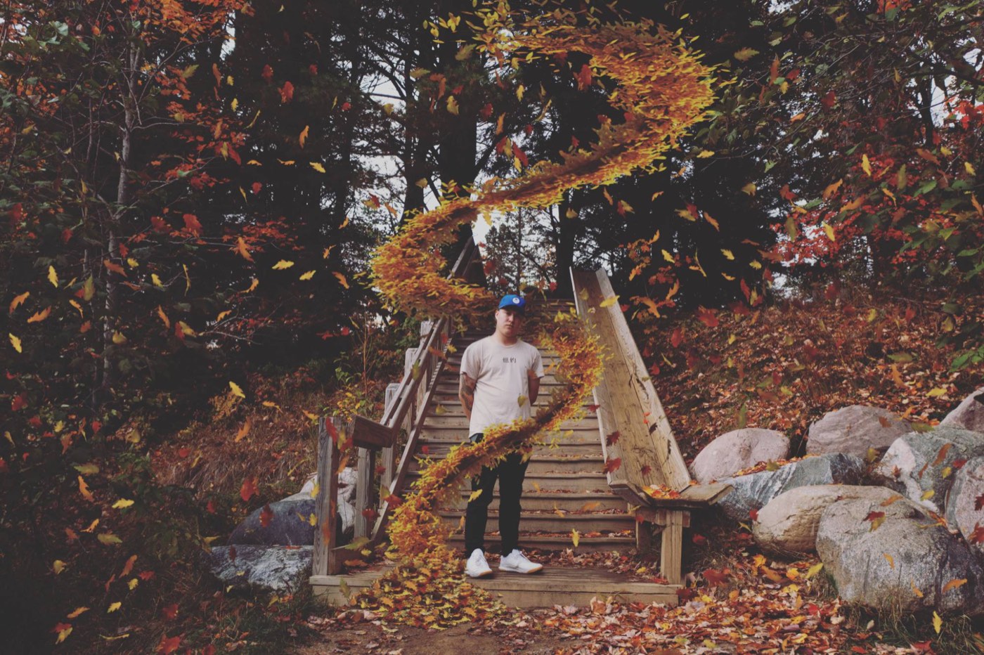 Dameon Spencer on wooden stairs surrounded by falling autumn leaves